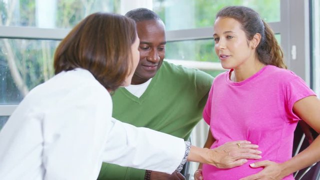  Friendly doctor talking to couple who are expecting a baby.