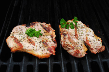 Two Perfectly Cooked Pork Chop on a Grill Garnished with Fresh Parsley