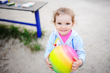 baby girl playing with a colored ball in the playground