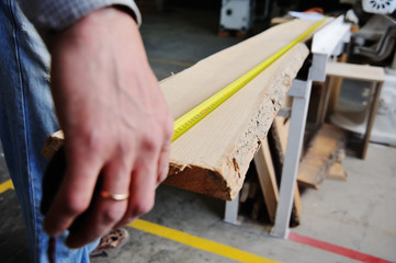 carpenter measures the wooden beam