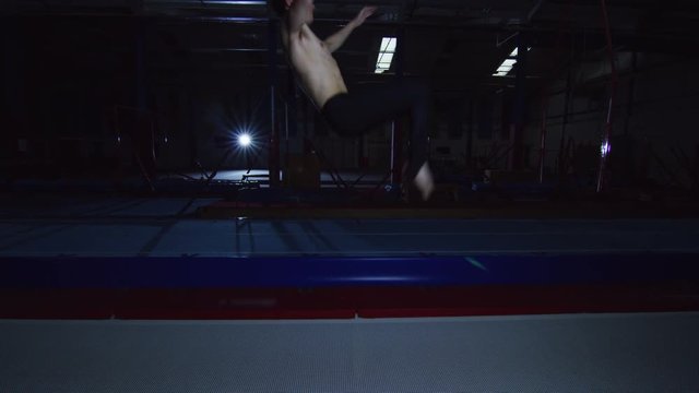  Professional male gymnast practicing flips on trampoline