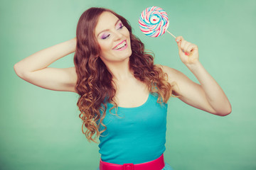 Smiling girl with lollipop candy on teal
