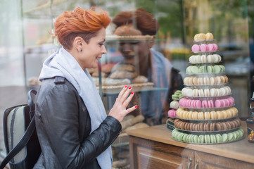Woman looks at showcase with colorful cakes