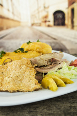 Traditional ecuadorian fritada typical serving with pork skin, meat, potato tortillas on white plate