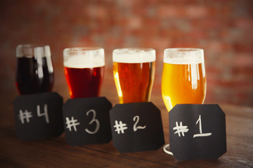 Glasses with different sorts of craft beer and numbering on wooden table. Retro stylization