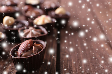 Chocolate sweets on wooden background with snow effect