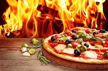 Foto op Plexiglas Delicious hot pizza on wooden table against fire flame background © Africa Studio