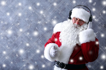 Santa Claus with headphones listening to music on gray wall background with snow effect