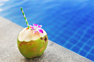 Fresh coconut drink with orchid flower near swimming pool