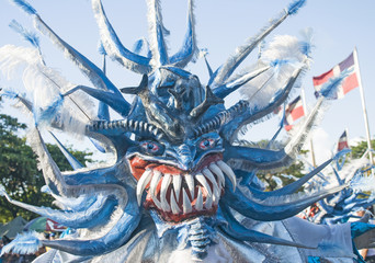 Carnival Monster with Dominican Flags Waving on Background - obrazy, fototapety, plakaty