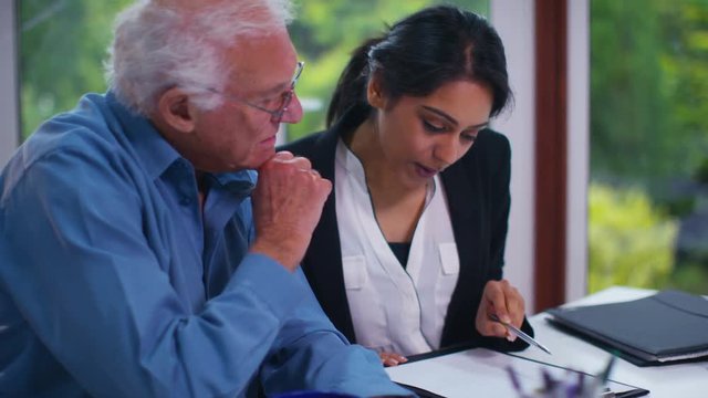  Senior man talking to young woman in office setting, could be a healthcare worker or financial adviser. Shot on RED Epic.