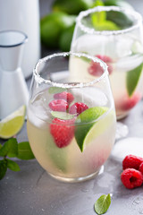 Cold summer cocktail with limes and raspberry