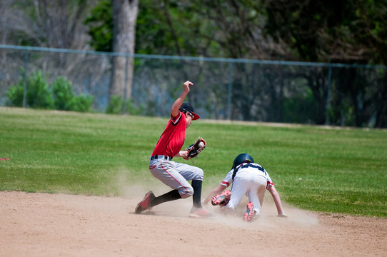 Teenage baseball shortstop tagging player out at second base.