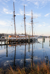 Three Masts at Pier / Three-masted schooner. White hull. From starboard aft quarter. Blue sky with...