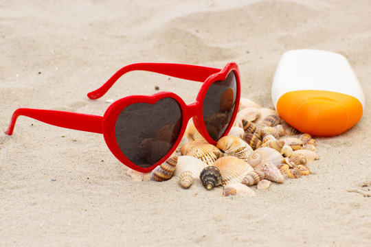 Seasonal concept, heap of shells, sunglasses and sun lotion