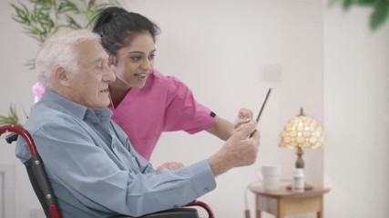  Caring home support nurse helping elderly man to use a computer