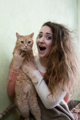 Comical young woman holding red cat