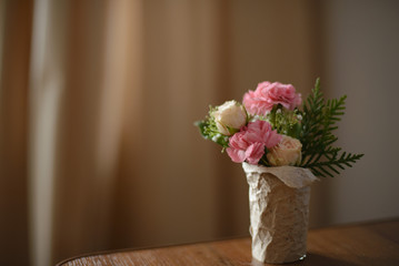 a small bouquet of roses and peony into a kraft pot on wooden table