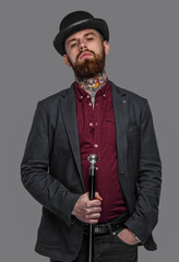 Tattooed bearded man in a suit holding cane