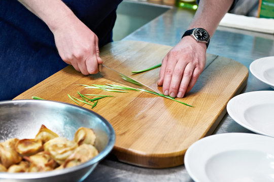 Cook cuts green onions for serving dumplings