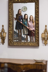 Three women on steps looking in mirror