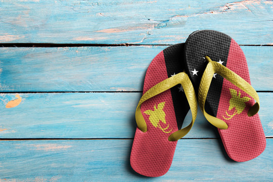 Thongs with flag of Papua New Guinea, on blue wooden boards