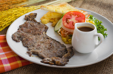 Beef steak with black pepper sauce , salad and French fries on s
