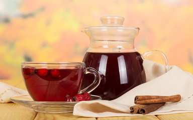 Pitcher, drink  cup  rosehip, vanilla sticks on  background  light wood.