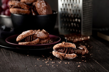Almond cookies and grapes and chocolate on dark wooden backgroun