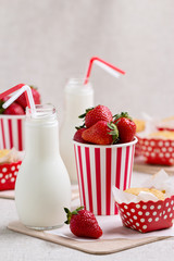 Delicious muffins, strawberries and milk in bottles.
