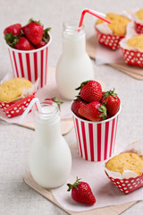 Delicious muffins, strawberries and milk in bottles.