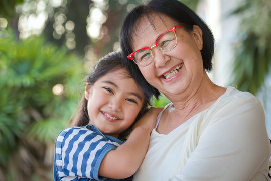 Happy little Asian girl hugging her grandmother