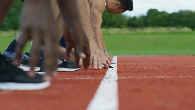 Group of athletes at running track, crouch at starting line before a race