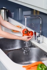 Woman washing tomatoes at kitchen sink