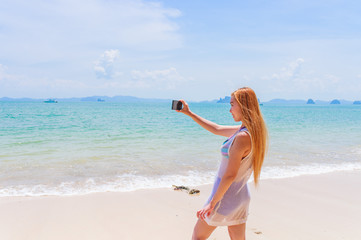 Fototapeta na wymiar Happy attractive blonde in bikini taking a self picture on a beautiful sunny beach 