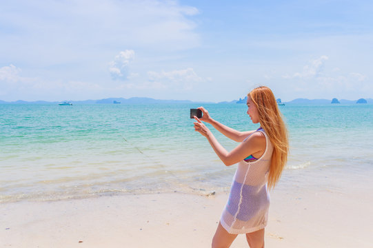 Happy attractive blonde in bikini taking a self picture on a beautiful sunny beach
