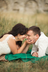 Happy wedding couple lying on green grass at the summer time