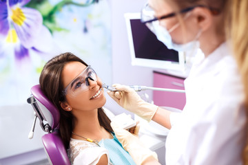Fototapeta premium Overview of dental caries prevention.Woman at the dentist's chair during a dental procedure. Beautiful Woman smile close up. Healthy Smile. Beautiful Female Smile 