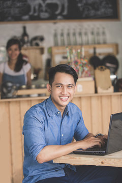 smiling man using laptop in the cafe