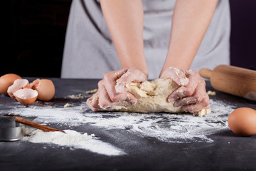 Baker is making cookies with wooden rolling pin ,eggs, flour, ci
