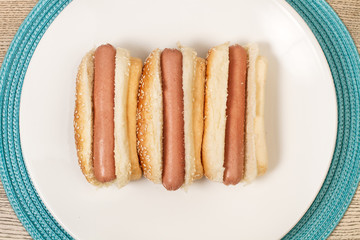 Perritos calientes hot dog sobre un plato redodno blanco. Vista superior y de cerca