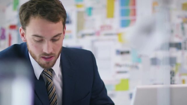  Cheerful businessman in office working on laptop computer