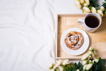 good morning - breakfast with bun and tea on wooden tray and flo