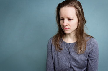 Portrait of a young sad disoriented woman in a gray blouse.