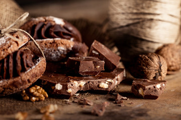 Chocolate cookies with pieces of chocolate and walnuts on old wo