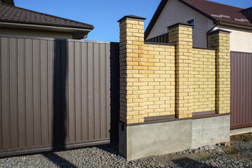 New modern yellow high metal fence in early spring