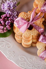 Butter cookies with pink ribbon and lilac flowers, top view