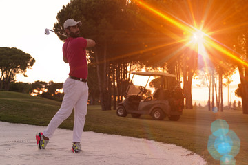 Obraz na płótnie Canvas golfer hitting a sand bunker shot on sunset