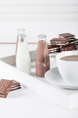 Cup of coffee on a white tray with brown cookies and chocolate m