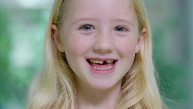  Close up portrait of little girl opening her mouth to show where she has lost one of her baby teeth. 